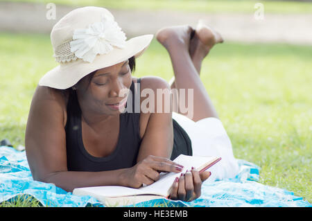Diese junge Frau liegen im Schatten eines Baumes ist ruhig lesen. Stockfoto