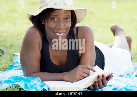 Diese junge Frau im Schatten eines Baumes liegen lesen ruhig Stockfoto