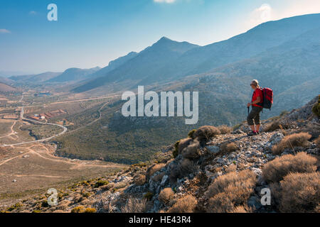 Weibliche Figur in rot mit Rucksack in Berge von Kalymnos, Griechenland Stockfoto