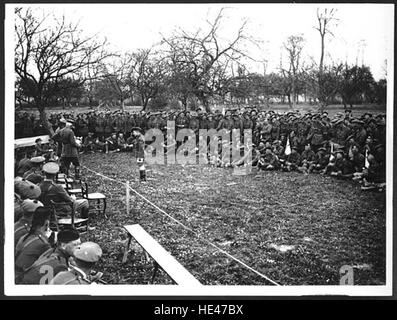 Dieses historische Bild zeigt einen Divisional Commander, der Preise verteilt, wahrscheinlich von einem früheren militärischen oder gesellschaftlichen Ereignis. Die Szene reflektiert eine feierliche Zeremonie, die die Anerkennung von Leistungen symbolisiert, sei es im Sport, im Militärdienst oder bei Gemeindeveranstaltungen, wobei Traditionen der Belohnung und Anerkennung hervorgehoben werden. Stockfoto