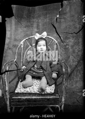 Ein Kind, das auf einem Stuhl sitzt, auf einer Glasplatte aus dem Costica Acsinte-Archiv in Rumänien festgehalten Stockfoto
