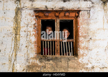 Eine junge Frau und ihr Sohn Kind schauen aus dem Fenster eines Bauernhauses Stockfoto
