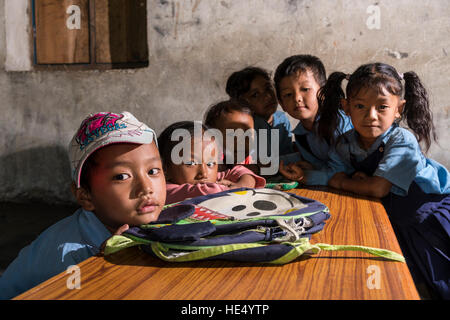 Eine Gruppe von Kindern in blaue Kleider sitzt an einem Tisch in der örtlichen Schule Stockfoto