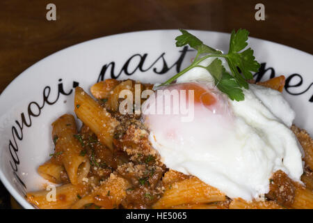 Penne all' Arrabbiata mit einem frisch pochierten Ei garniert. Stockfoto