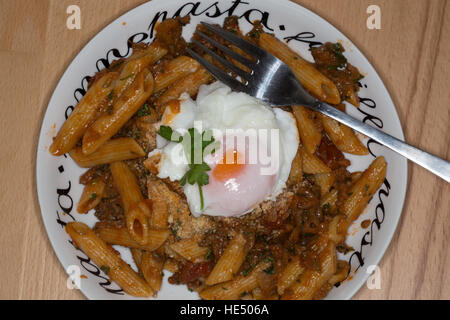 Penne all' Arrabbiata mit einem frisch pochierten Ei garniert. Stockfoto