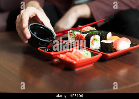 Männliche Hände gießt Soße in einen Teller. Sushi set Stockfoto