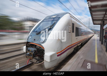 El Escorial, Spanien - 13. Dezember 2016 - Renfe S-598 Mittelstrecke Zug mit unscharfen Hintergrund Ankunft am Bahnhof in Bewegung Stockfoto