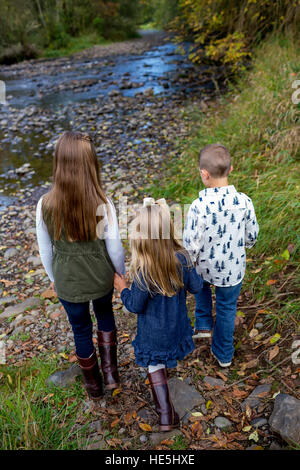 Drei Kinder, die Geschwistern in einem offenen Lebensstil Foto im Freien an den Ufern des McKenzie River in Oregon. Stockfoto