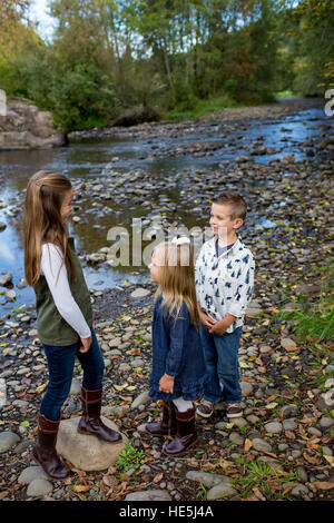 Drei Kinder, die Geschwistern in einem offenen Lebensstil Foto im Freien an den Ufern des McKenzie River in Oregon. Stockfoto