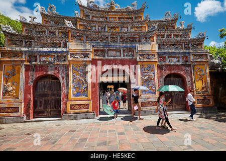 Touristen, die durch ein reich verzierte Eingangstor zum Tempelgelände von To Mieu laufen. Kaiserstadt (Zitadelle), Hue, Vietnam. Stockfoto