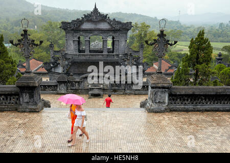 Touristen, die im Regen auf einer Terrasse am Saluation Court des Grabes von Khai Dinh (Ung Grab) spazieren. Hue, Vietnam. Stockfoto