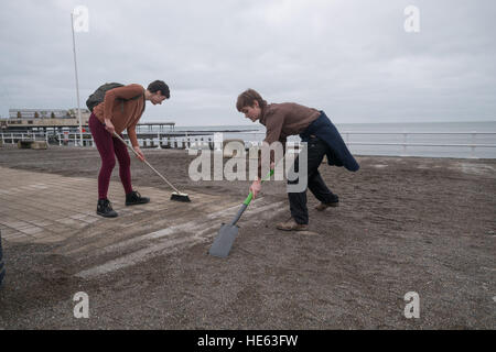 Aberystwyth Wales UK, Sonntag, 18. Dezember 2016 Aberystwyth University Studenten ELEANOR CLIFTON (22, Bürsten) und XANDER König (20, mit Schaufel), beide ursprünglich aus Wiltshire, habe alle von diesem Sonntagnachmittag Bürsten und Schaufeln Sand abseits die Promenade in Aberystwyth nach der stürmischen See Anfang dieser Woche. Sie haben sich auf eigene Faust, ohne Zutun der Gemeindebehörde Eleanors Partner zu ermöglichen, die ein Rollstuhl-Benutzer ist, und viele andere Leute eingeschränkten Mobilität, in den Genuss die Strandpromenade Credit: Keith Morris/Alamy Live-Nachrichten Stockfoto