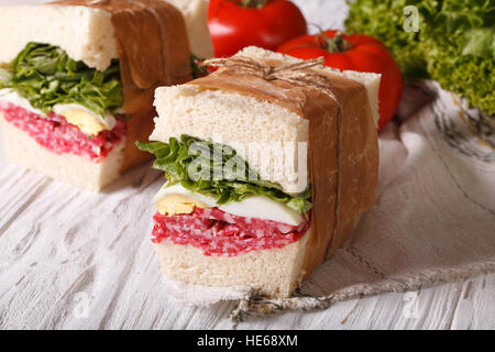 Sandwiches mit Salami eingewickelt in Papier Nahaufnahme auf dem Tisch. horizontale Stockfoto