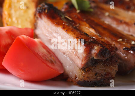 gebratene Schweinerippchen und frischen Tomaten auf der Platte-Makro. horizontale Stockfoto
