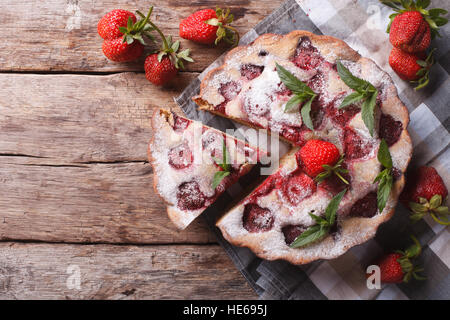 Köstliche geschnittenen Torte mit frischen Erdbeeren und Minze auf einem Tisch. horizontale Ansicht von oben. Rustikaler Stil Stockfoto