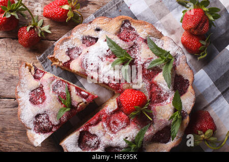in Scheiben geschnitten-Torte mit frischen Erdbeeren und Minze-close-up auf dem Tisch. horizontale Ansicht von oben. Stockfoto