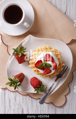 Waffeln mit frischen Erdbeeren, Sahne und Kaffee mit einer Tabelle Großaufnahme. vertikale Ansicht von oben Stockfoto