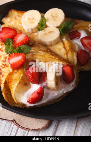 Leckere Crepes mit Erdbeeren, Bananen und Sahne Nahaufnahme.  Vertikal Stockfoto