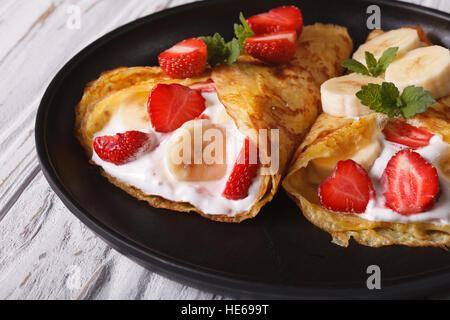 Crepes mit Erdbeeren, Bananen und Sahne Nahaufnahme auf einer Platte. horizontale Stockfoto