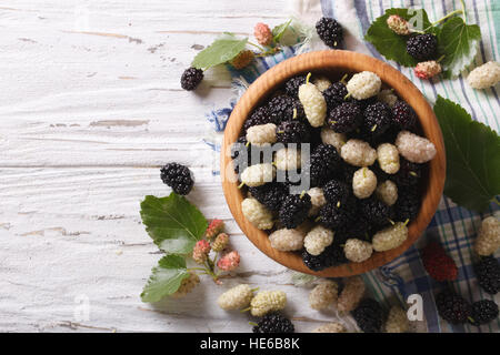 Weiße und schwarze Maulbeeren in einer Holzschale auf dem Tisch. horizontale Ansicht von oben Stockfoto