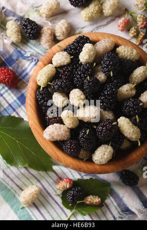 Reife weiße und schwarze Maulbeeren in einer Holzschale auf der Tabelle Nahaufnahme. vertikale Ansicht von oben Stockfoto