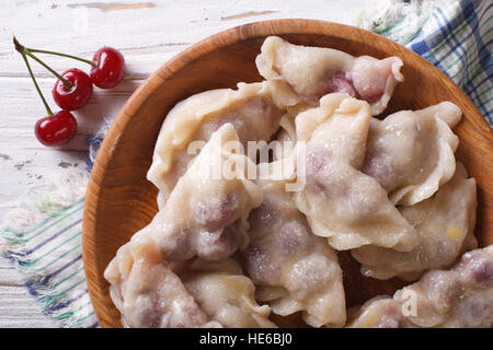 süße Knödel mit Kirschen in einer Holzschale.  horizontale Ansicht von oben Stockfoto