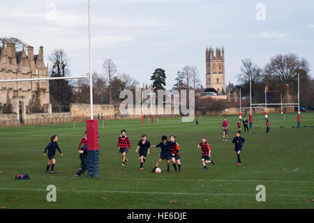 Kinder von Christchurch Cathedral School, Oxford Fußballspielen auf Spielfeldern mit Magdalen Tower im Hintergrund Stockfoto