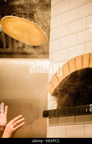 Pizzateig geworfen vor Pizza-Ofen Stockfoto