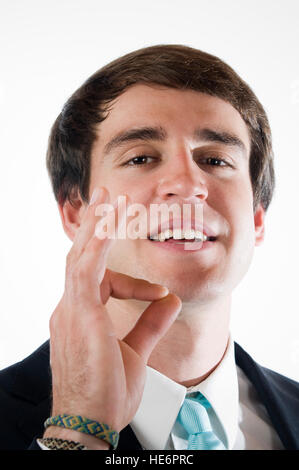 Kopf und Schulter Blick eines jungen Mannes in Business Kleid zeigt die "OK" Zeichen vor weißem Hintergrund mit der rechten Hand. Stockfoto