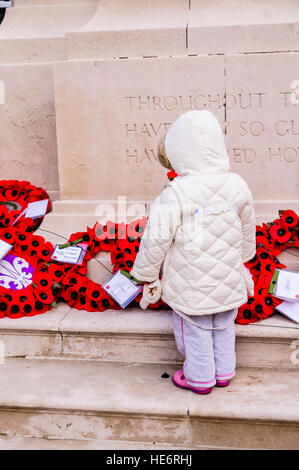 Ein junges Mädchen schaut Mohn Kränze am Ehrenmal, Belfast. Stockfoto