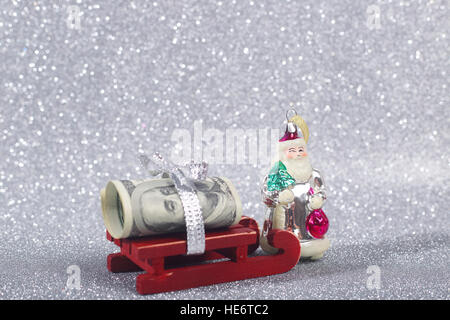 Geld bringt der Weihnachtsmann auf seinem Schlitten auf Glitzer Hintergrund Stockfoto