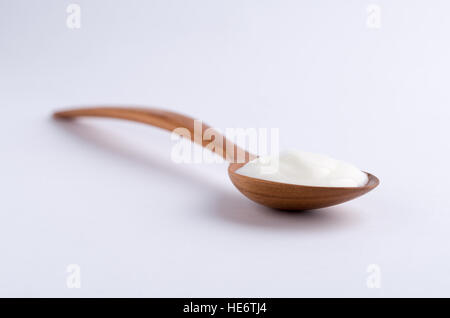Holzlöffel voller weißer Joghurt auf weißem Hintergrund. Stockfoto