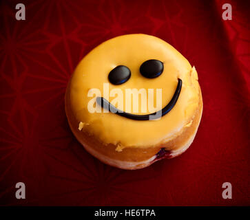 Smiley Gesicht Jelly Donut mit Zitronenglasur Sahne und Schokolade Stockfoto