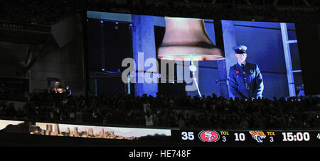 Ein Royal Air Force senior Aircraftsman läutet die Glocke im dritten Quartal von den Jacksonville Jaguars gegen San Francisco 49ers National Football League Spiel 27. Oktober 2013, im Wembley Stadion in London, England. Die Glocke wurde geläutet viermal zu Ehren von Männern und Frauen, Vergangenheit und Gegenwart, in ihren Ländern. Die NFL gab US Air Force Airman 1. Klasse James Taylor, 100. Sicherheit Kräfte Squadron Streifenpolizist und US Air Force Airman Sara V. Summers, 48. Sicherheit Kräfte Squadron Streifenpolizist von RAF Lakenheath, die Möglichkeit zu rivalisierenden Fußball Mannschaften aufs Feld.  Senior Airman Stockfoto