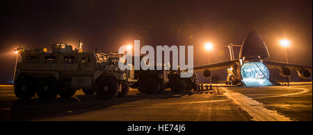 Flieger aus dem 9. Airlift Squadron und 455. Expeditionary Luft Port Squadron mit Marines aus der Marine Expeditionary Brigade bereiten Fahrzeuge in einer C - 5 M Super Galaxy 6. Oktober 2014, im Camp Bastion, Afghanistan zu laden. Piloten und Marines geladen mehr als 266.000 Pfund Ladung auf die C - 5M im Rahmen der retrograden Operationen in Afghanistan. Besatzungen für die retrograden Operationen, verwaltet von der 385th Air Expeditionary Gruppe Ablösung 1, übertraf 11 Millionen Pfund Fracht transportiert in einem Zeitraum von 50 Tagen. Während dieses Zeitraums ope Besatzungen unter den 385th AEG brach Air Mobility Command der Stockfoto