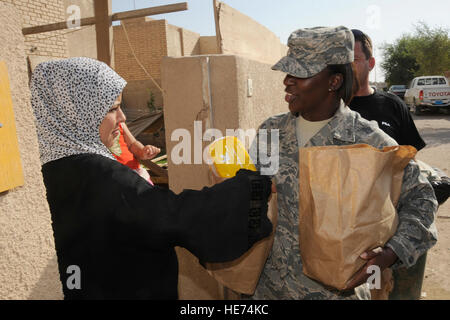 Bagdad, Irak-Staff Sgt Shamonn Mason, absichtliche 447th Expeditionary Force Support Squadron und Krise Aktion Planung und Ausführung Segmente Betreiber, Hände eine irakische Frau gespendet-Elemente für ihre Familie hier 24. Juli 2009. Fünfundvierzig Flieger und Soldaten, die sich freiwillig zu besuchen und verteilen Sachspenden lokale irakische Familien als Bestandteil der Sather Air Base gute Nachbarn-Programm. Die Pakete enthalten Elemente der irakischen Familien haben vielleicht eine harte Zeit, ansonsten wie Hygieneartikel, Trockenfutter, Spielzeug für Kinder, Snacks und Leckereien. Sergeant Mason wird von Randolph Air bereitgestellt. Stockfoto