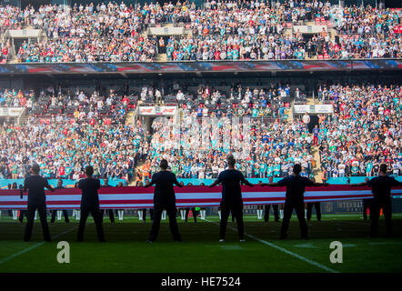 Flieger der Royal Air Force Lakenheath, England, nehmen am 4. Oktober 2015 an einer Zeremonie teil, bei der US-amerikanische und britische Flaggen vor dem Spiel Miami Dolphins vs. New York Jets im Wembley Stadium in London präsentiert werden. Die Zeremonie symbolisiert die militärische Zusammenarbeit und Partnerschaft zwischen den USA und Großbritannien. Stockfoto