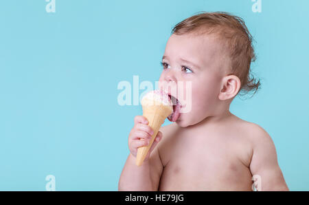 Entzückende Babymädchen Essen ein Eis auf einfarbigen blauen Hintergrund Stockfoto