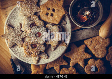 Hausgemachte Weihnachten Lebkuchen und Linzer Kekse mit Marmelade, Puderzucker, auf Backblech legen, oben flachen Ansicht, weiche Nebel Effekt, Vintage Stockfoto