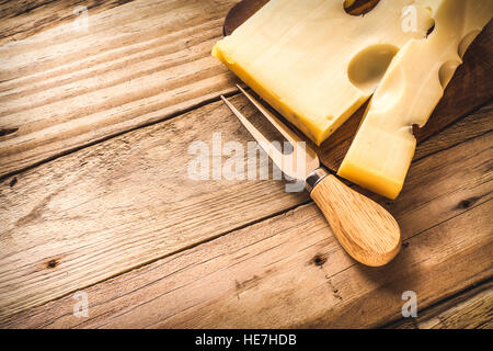 Maasdam Käse auf eine dunkle Board oben rechts Schnittwinkel mit Käse Gabel, Ansicht von oben flach Stockfoto