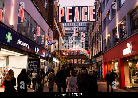 Straßenansicht der Carnaby Street voll mit Touristen und Menschen beim Einkaufen mit großen hellen Weihnachtsschmuck Stockfoto