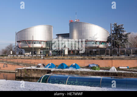 Der Europäische Gerichtshof für Menschenrechte (EMRK), mit einem Touristenboot, das Zelte passiert, während Demonstranten vor dem Gebäude campen. Straßburg, Frankreich Stockfoto