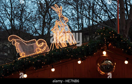 Lichter und Weihnachtsschmuck: ein Schlitten mit Rentieren auf eine rote Hütte Stockfoto