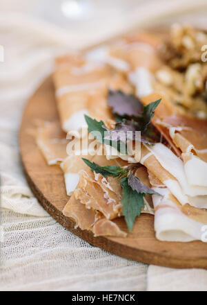 Prosciutto di Parma Schinkenscheiben und frischem Basilikum Blätter auf Holzbrett. Stockfoto