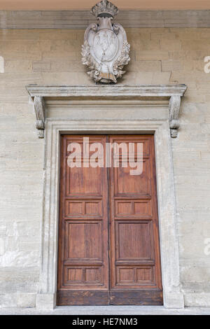 Große alte Holztür mit Stein Wappen im Stadtzentrum von San Marino auf der Wand der Basilika di San Marino, Nahaufnahme Stockfoto