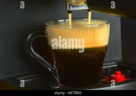 Ganz in der Nähe Aussicht auf Kaffee Maschine Gießen Espresso in die interessante, stimmungsvolle Licht mit deutlich sichtbar, leicht nicht scharf Rinnsale Gießen cof Stockfoto