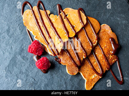 Pfannkuchen in die Form eines Herzens mit Schokolade Sirup und Himbeeren am Valentinstag. Stockfoto