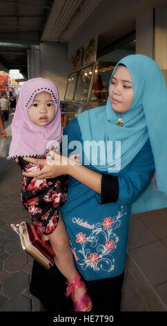 Junge muslimische Mutter und baby-Tochter, beide tragen traditionelle Hijab Kopfbedeckung. S. E. Asien Thailand Stockfoto