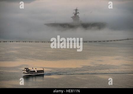 Nebel vom Pazifischen Ozean Rollen umgibt die USN Nimitz-Klasse-Flugzeugträger USS Ronald Reagan in einer dicken Wolke, während eine lokalen Fähre vorbei neben 11. Februar 2014 in San Diego, Kalifornien. Stockfoto