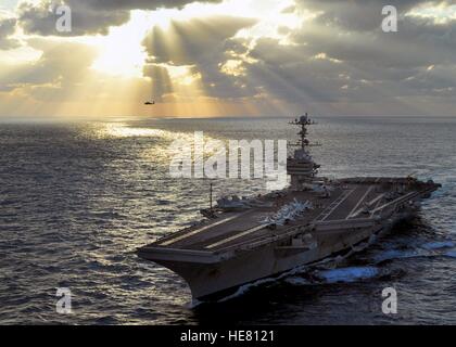 Ein Sikorsky SH-60 b Seahawk Hubschrauber fliegt neben dem USN Nimitz-Klasse-Flugzeugträger USS George Washington, wie sie bei Sonnenuntergang 18. November 2009 im Pazifischen Ozean transit. Stockfoto